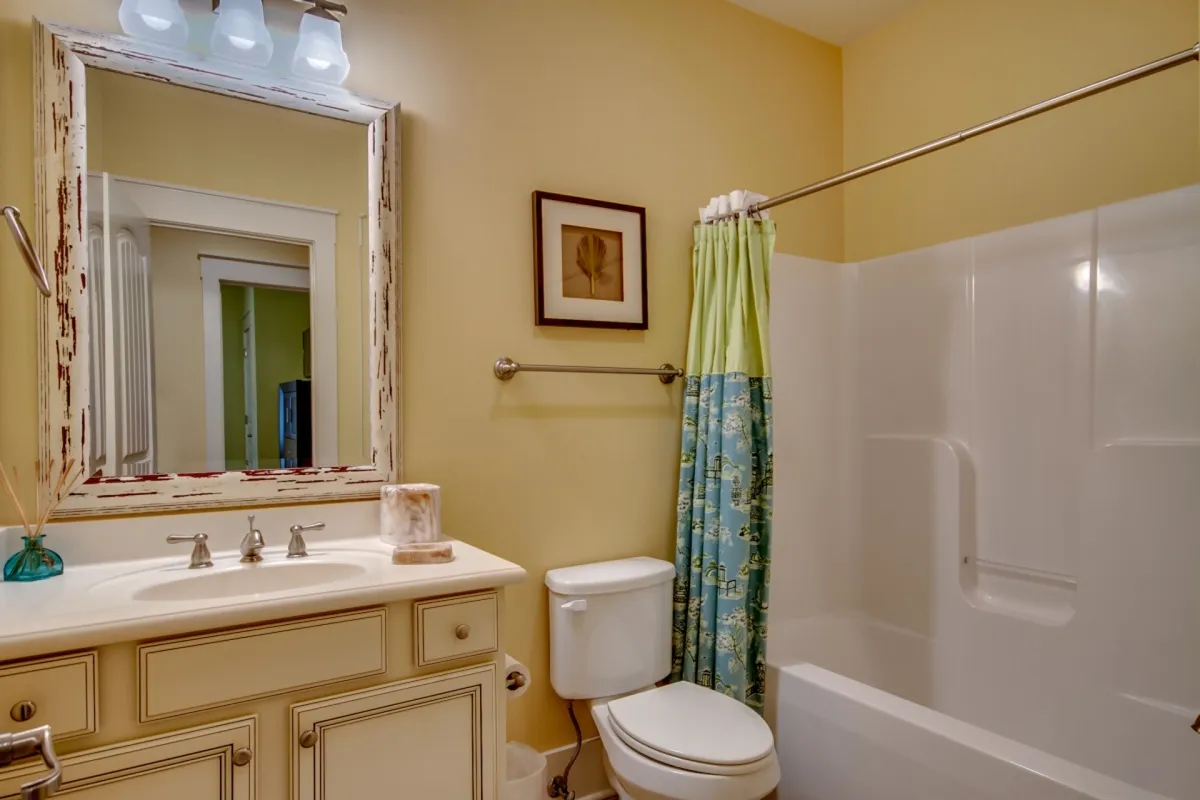 A bathroom with a fresh, modern feel, featuring a vanity with sink, mirror, shower area, towel rack, and decorative artwork. The overall vibe is calm and refreshing, suitable for busy mornings or quiet reflection.