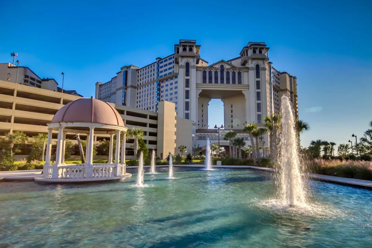 This image captures the exterior pool complex, featuring tranquil fountains, a gazebo, and the resort's elegant architectural details. The space is open and inviting, ideal for relaxation and social gatherings by the water, conveying a sense of luxury and fun in the sun.
